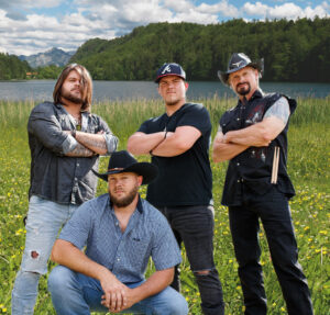 Naturally Southern country band members posing in a field by a lake