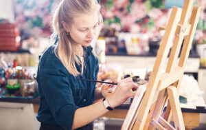 young-woman-artist-working-on-painting-in-studio