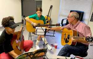 students practice guitar with instructor