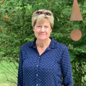artist Susan Miller in a blue shirt standing in her back yard