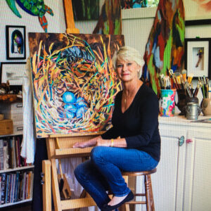 artist Jill Bright sitting at a painting in her studio
