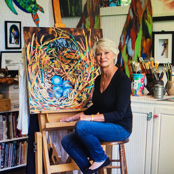 artist Jill Bright sitting at a painting in her studio