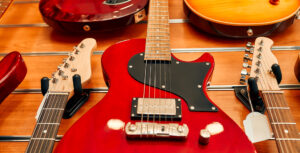 group of guitars lying on a table with a bright red guitar in focus