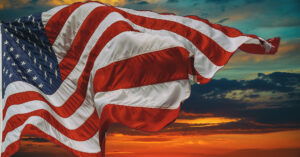 an American flag billowing in front of a gorgeous red sunset