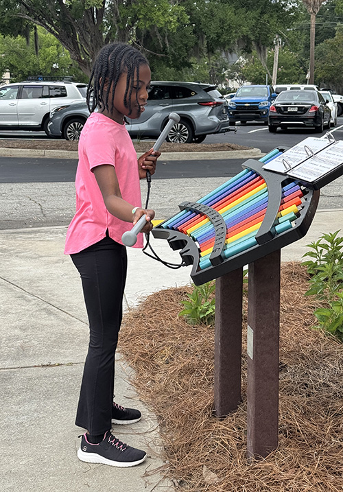 young girl plays the outdoor xylophone
