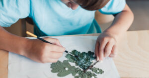 young child doing leaf art for camp